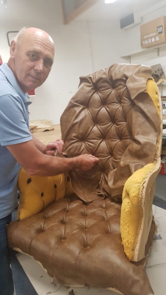 Dorus de Vries (eigenaar) is bezig met een herstoffering met leer.  